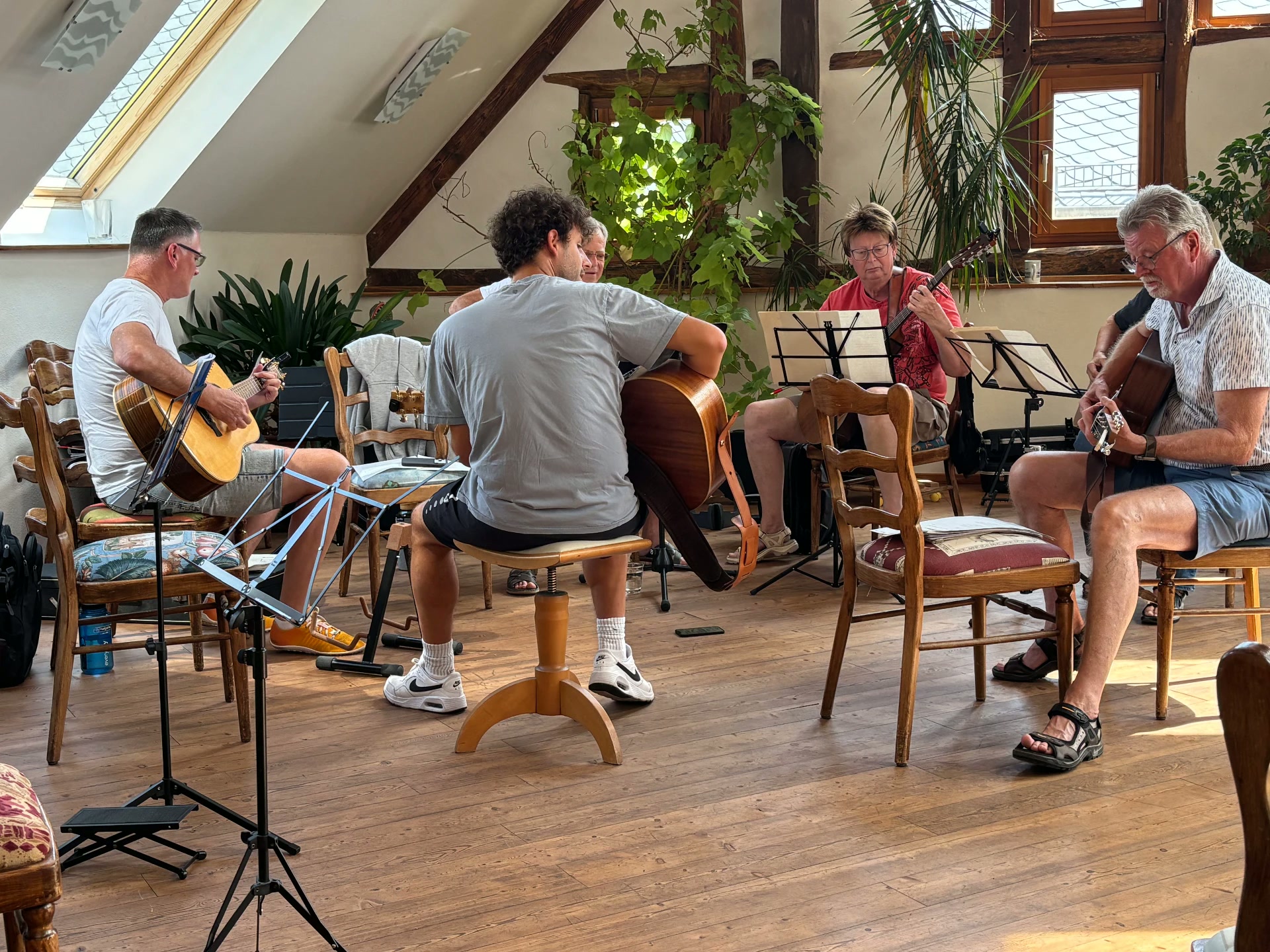 Kleine Gruppe spielt in einem hellen Dachraum mit Notenständern zusammen