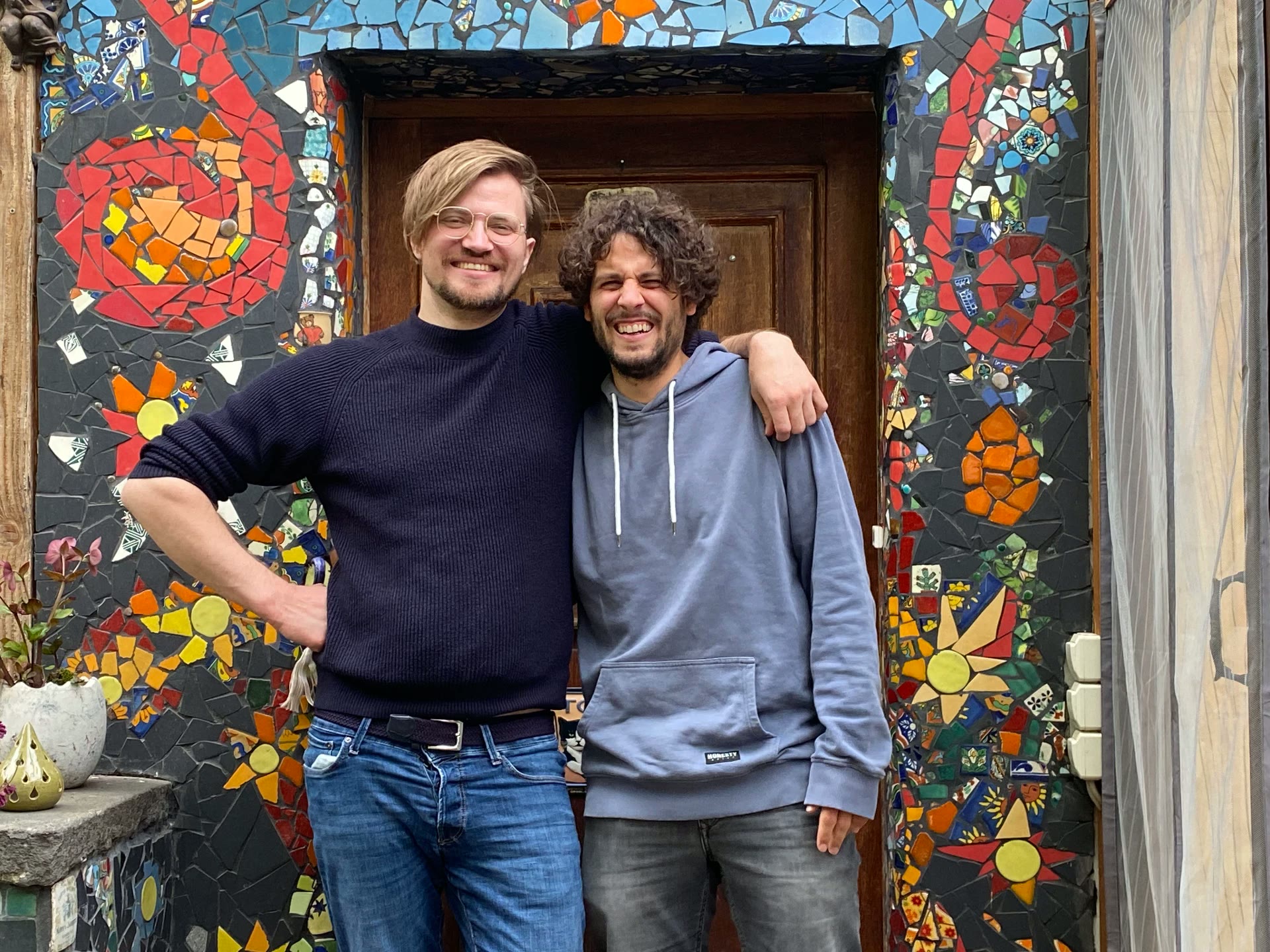 Tillmann Zock und Andreas Januschke lachend vor einer Mosaiktür